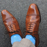 Man wearing baby blue and white polka dot socks, and dress shoes.