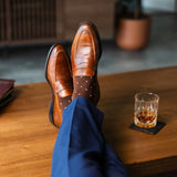 Men's dress socks with a rich chocolate base and clean white accents, paired with navy trousers and brown leather loafers