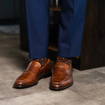 Rich chocolate brown men's dress socks with clean white accents, paired with navy trousers and brown leather loafers