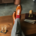 Red patterned sock worn with brown leather shoes and grey trousers
