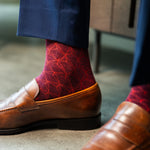 Red patterned sock worn with brown leather shoes and navy trousers