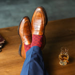 Red patterned sock worn with brown leather shoes and navy trousers