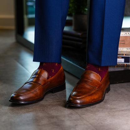 A deep red men's dress sock with a gold t-sun pattern