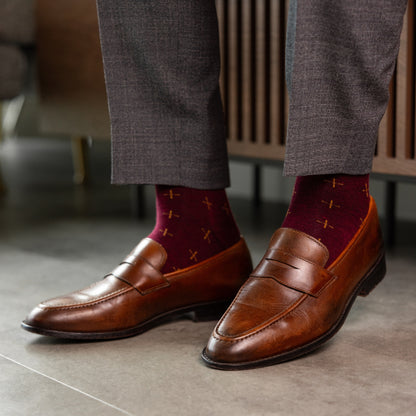 A deep red men's dress sock with a gold t-sun pattern