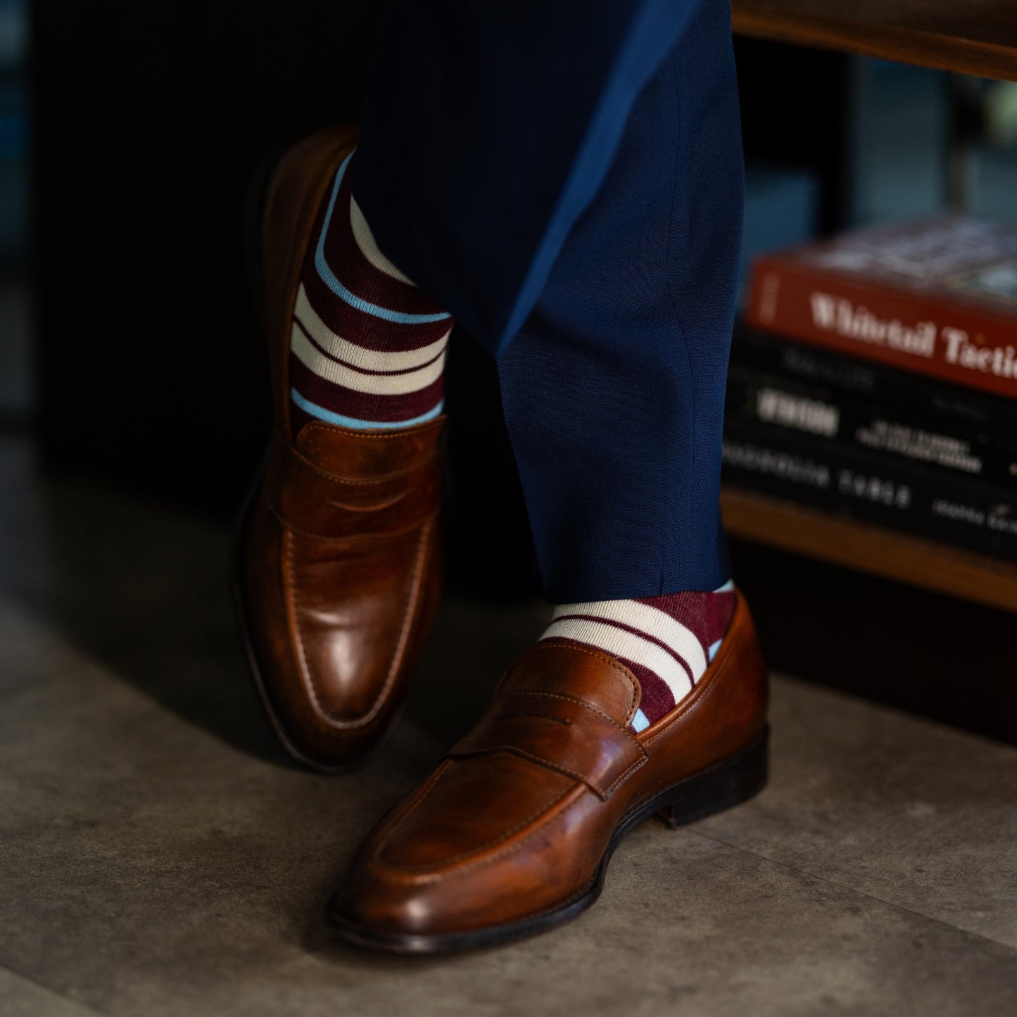 A cranberry red men's dress sock with cream and light blue stripes.