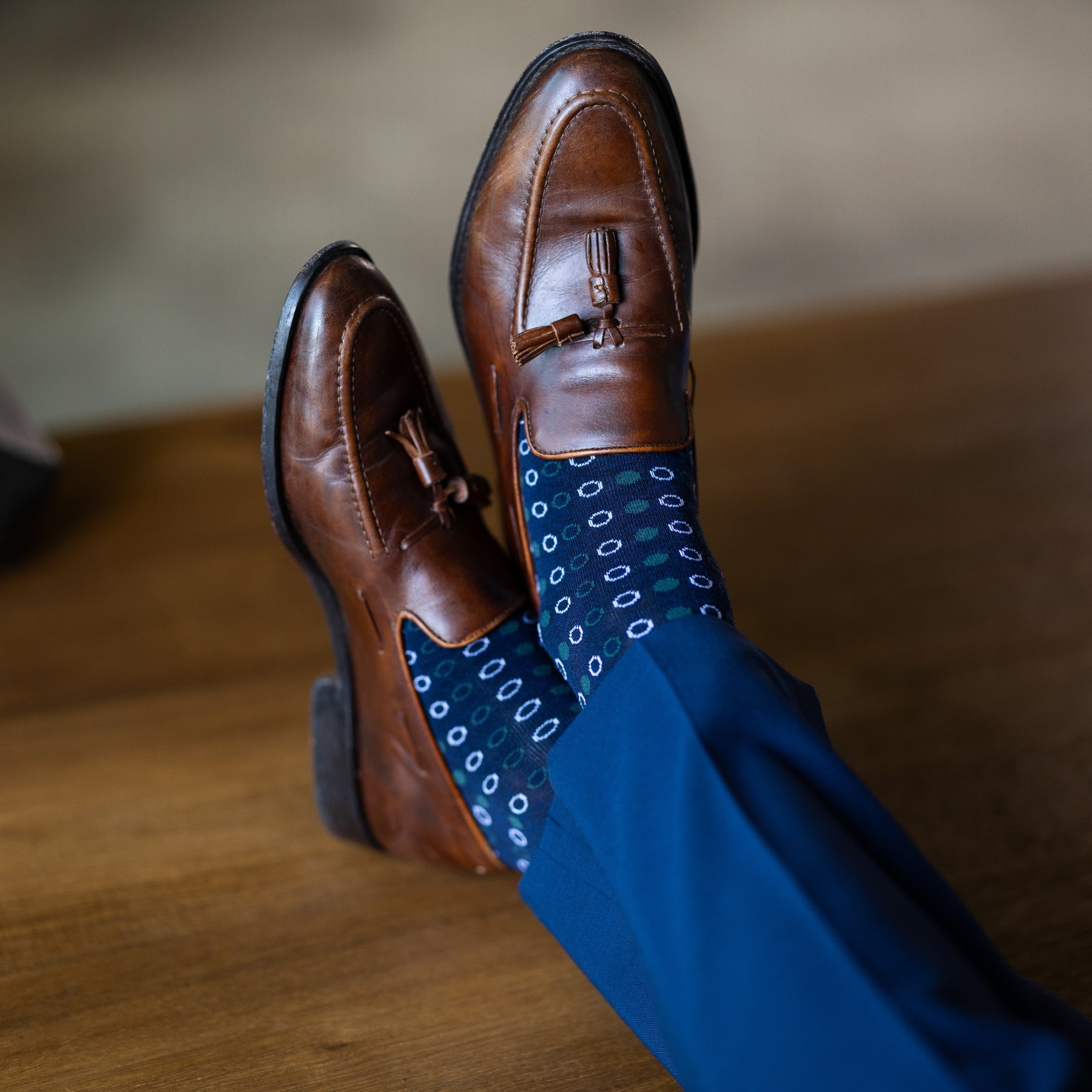 A navy blue men's dress sock with green and white polka dots