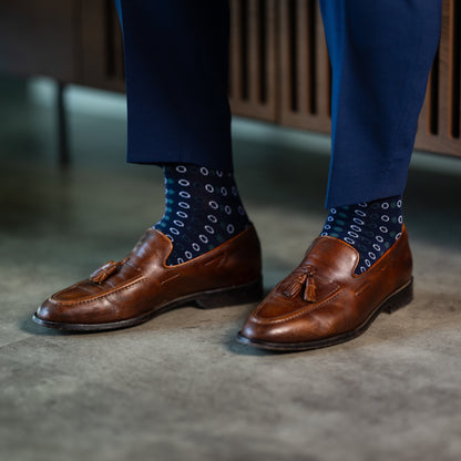 A navy blue men's dress sock with green and white polka dots