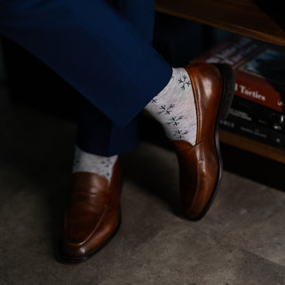 A light grey men's dress sock with a black snowflake pattern