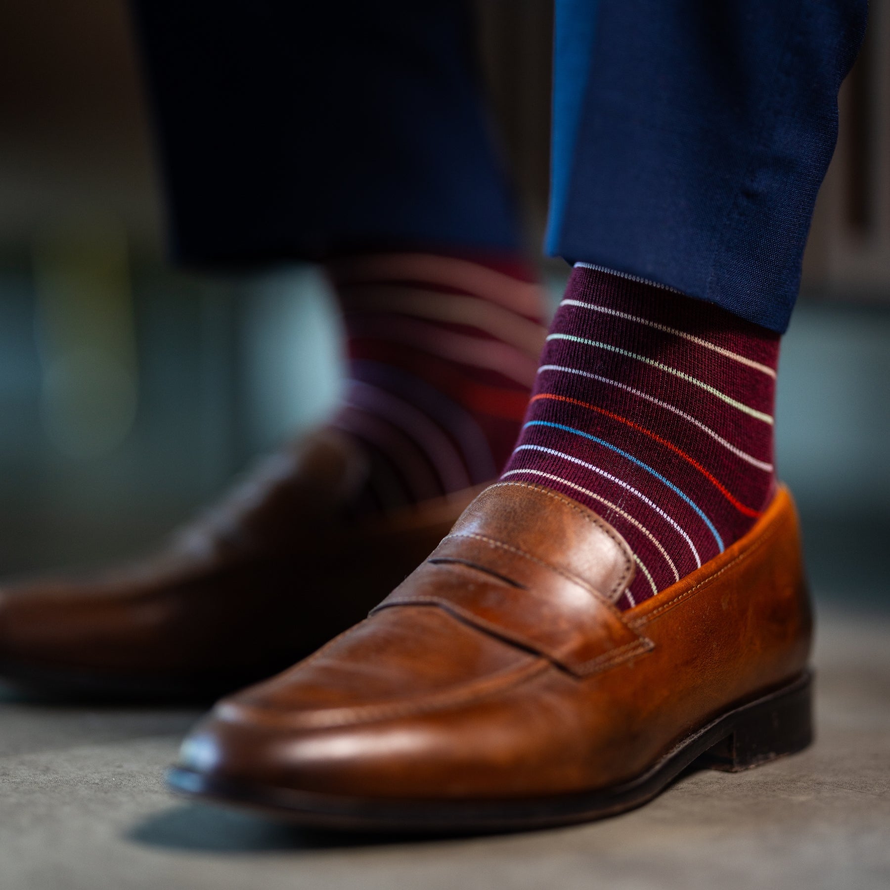 Deep red men's dress sock with multi-colored thin stripe pattern