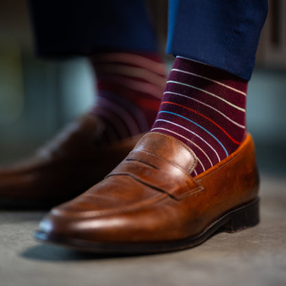 Deep red men's dress sock with multi-colored thin stripe pattern