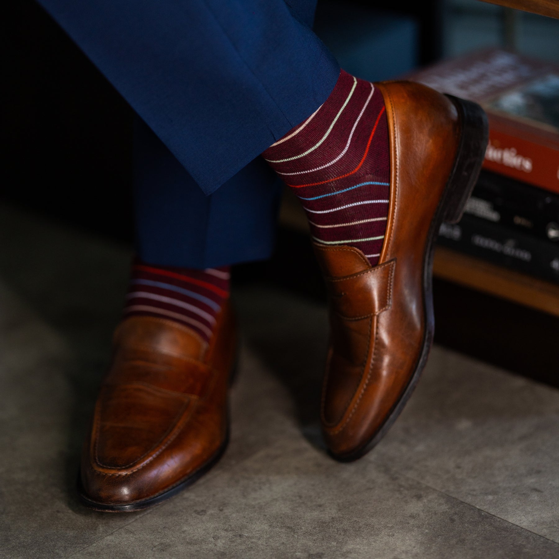 Deep red men's dress sock with multi-colored thin stripe pattern