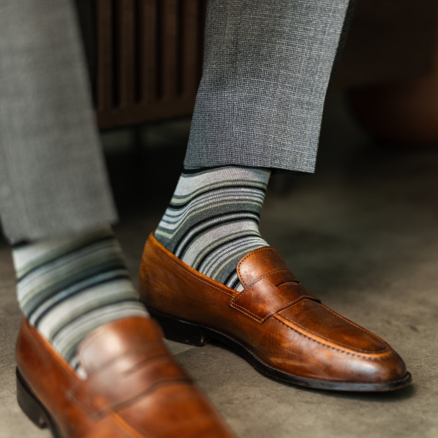 A cool men's dress sock combination of grey, sage, and olive stripes designed for refined versatility and subtle sophistication. 