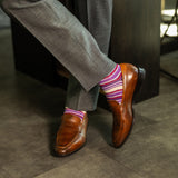 Person wearing purple stripe men's dress socks with brown shoes and gray pants on a checkered floor.