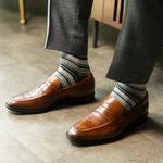 Striped socks worn with brown loafers and grey trousers