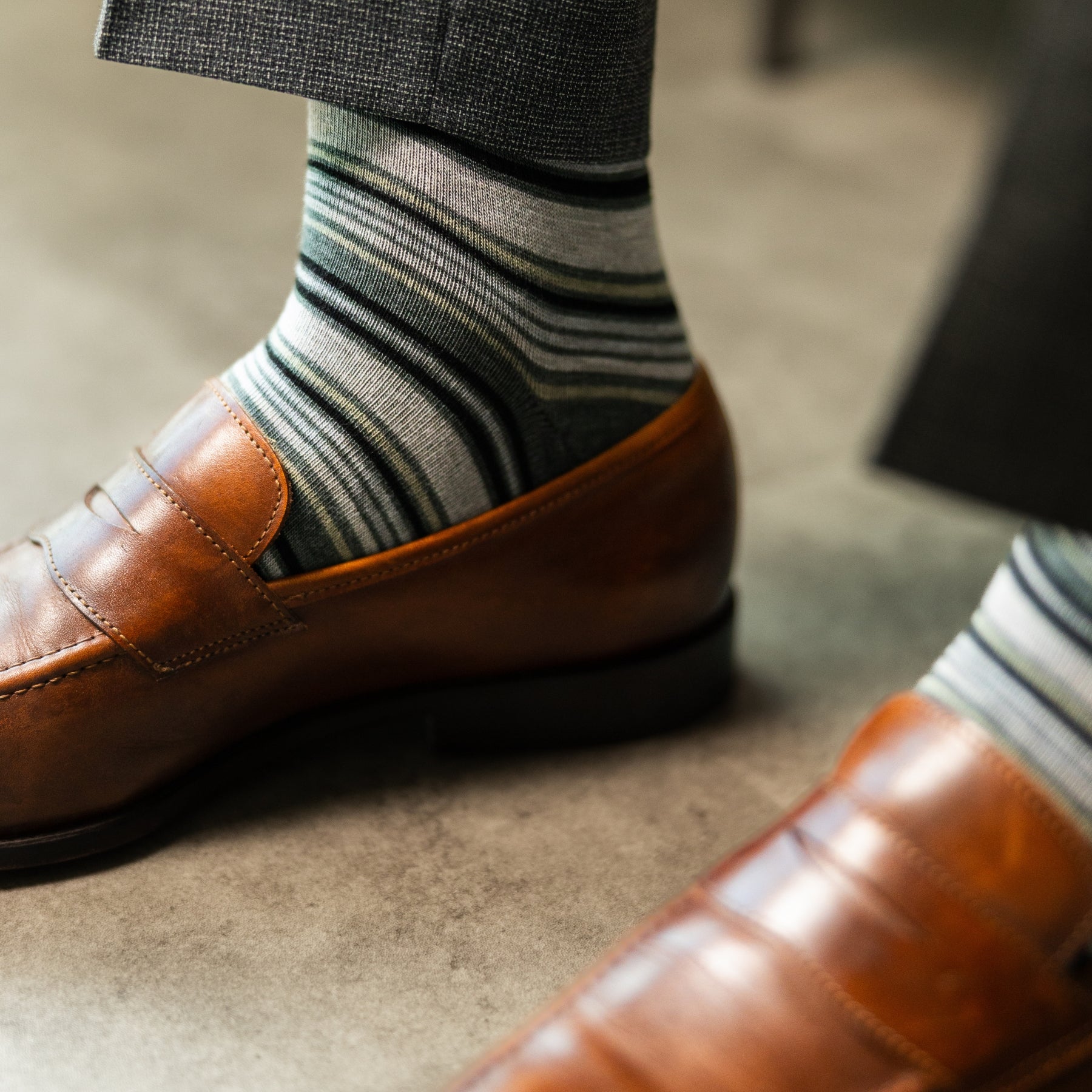 A cool men's dress sock combination of grey, sage, and olive stripes designed for refined versatility and subtle sophistication. 