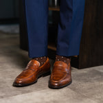 Rich chocolate brown men's dress socks with clean white accents, paired with navy trousers and brown leather loafers