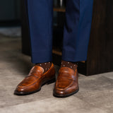 Rich chocolate brown men's dress socks with clean white accents, paired with navy trousers and brown leather loafers