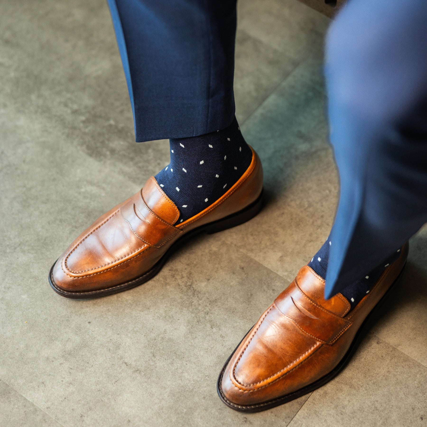 Brown leather shoes and navy polka dot socks worn with navy pants.
