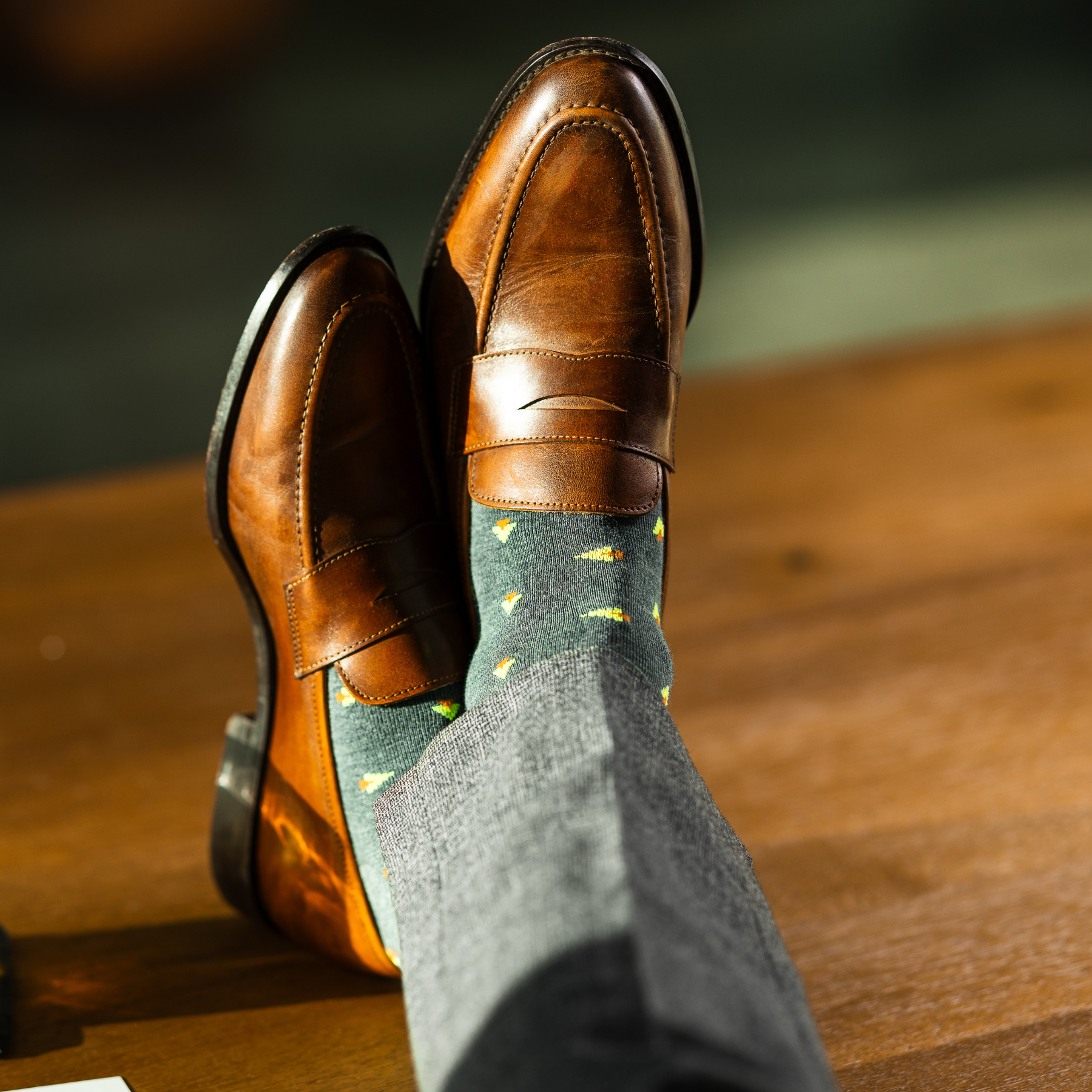 A charcoal-green sock with warm orange and green pine tree motifs, designed to add a subtle seasonal touch with refined, modern appeal.