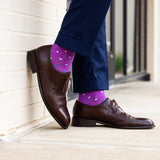Brown dress shoes and purple polka dot socks against a neutral background