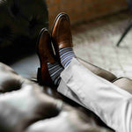a man wearing grey, blue, and white striped men's dress sock
