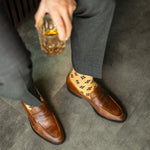 A light rust-orange men's dress sock with a bold black leaf motif