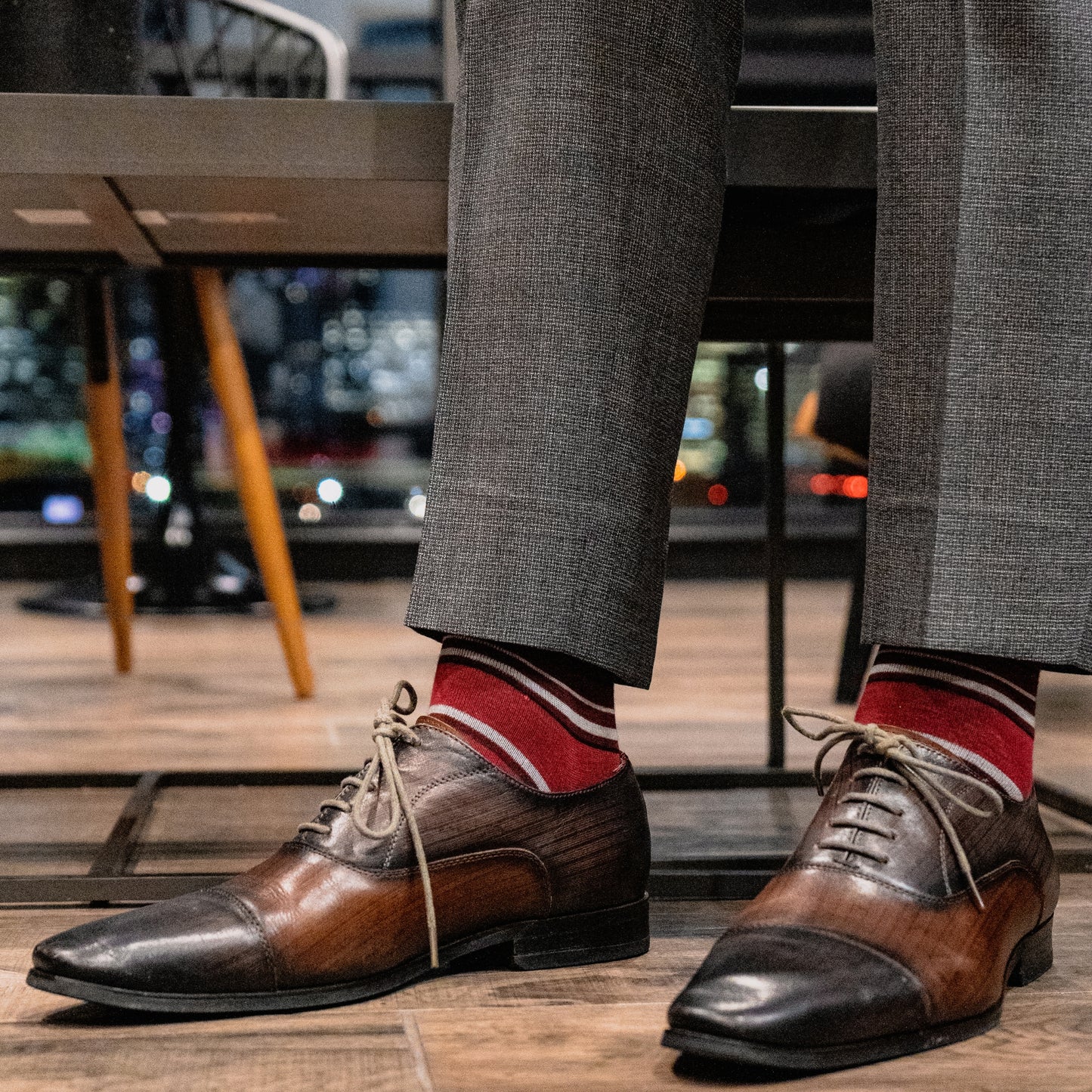 a men's dress sock with varying hues of red, with white and black contrasting stripes