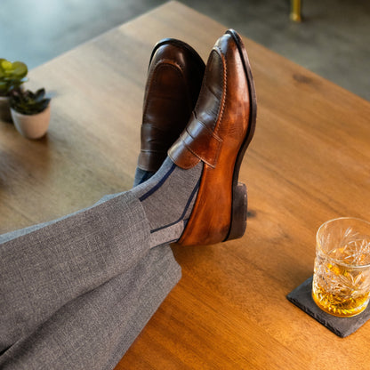 A grey men's dress sock with a navy blue vertical stripe pattern