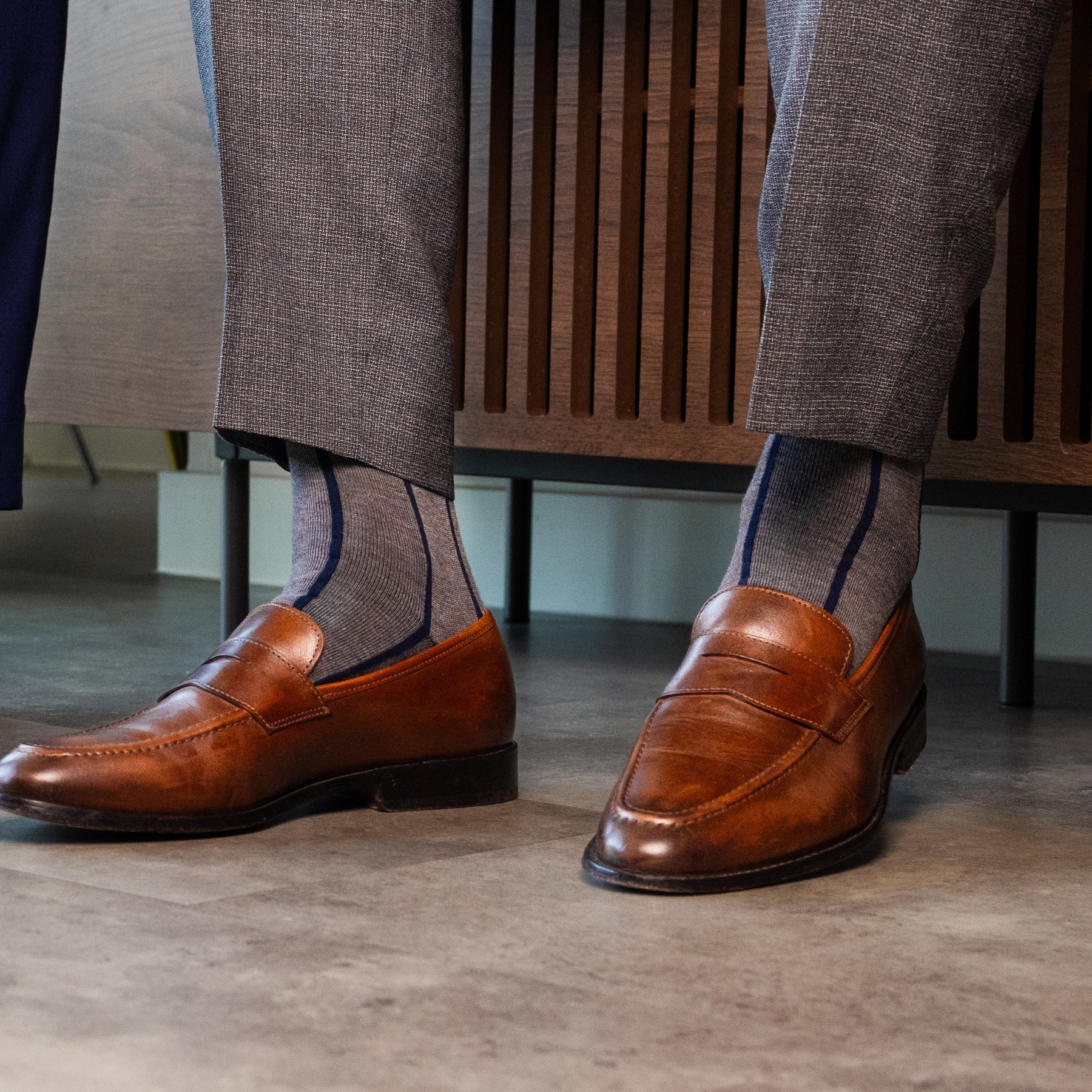 A grey men's dress sock with a navy blue vertical stripe pattern