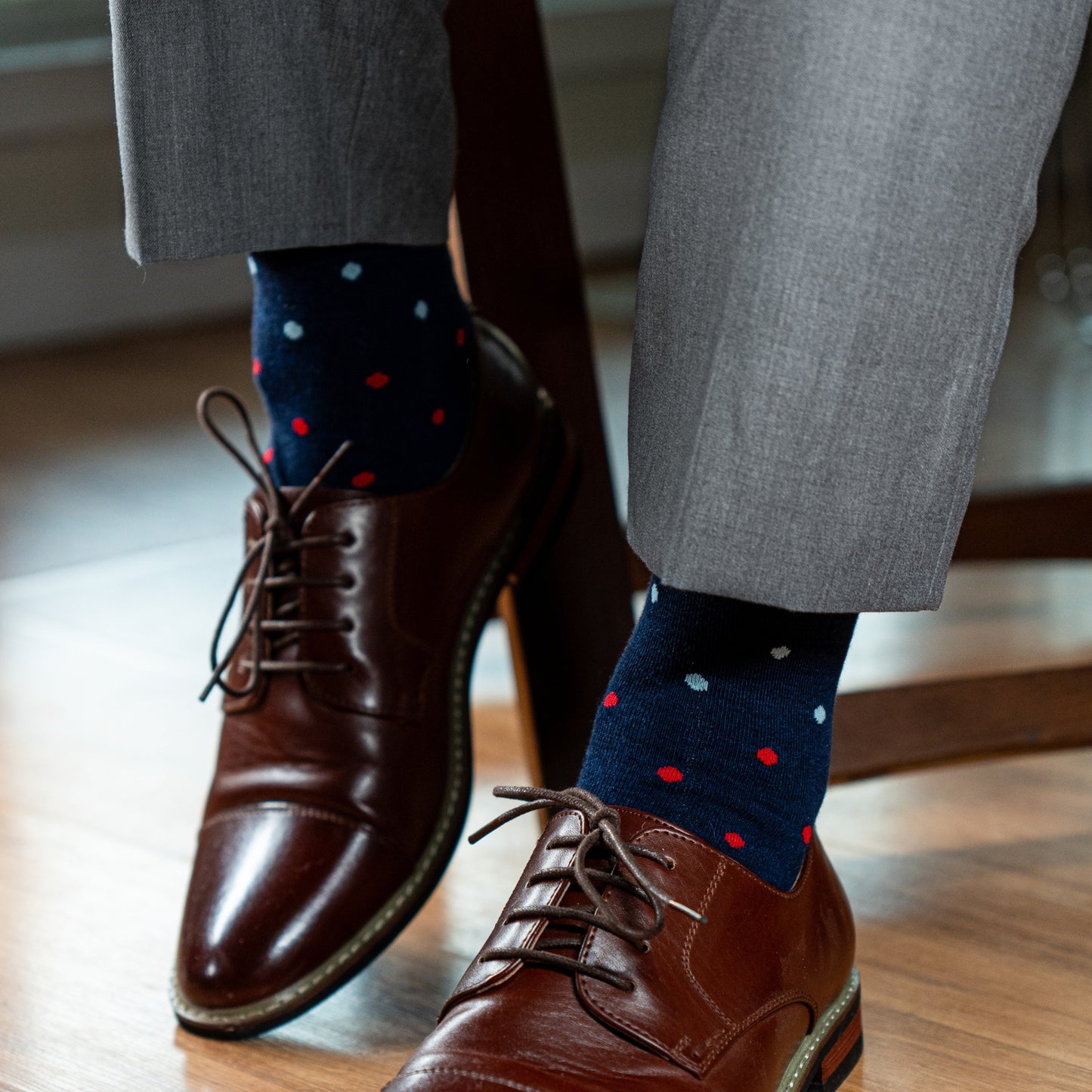 A Navy men's dress sock with red, pink and light blue polka dots