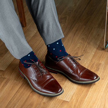 A Navy men's dress sock with red, pink and light blue polka dots