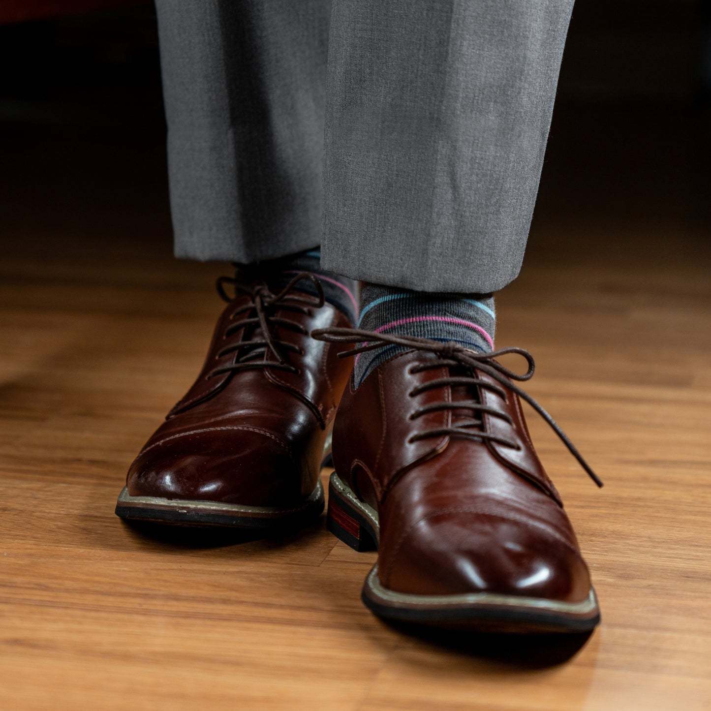 A grey men's dress sock with navy blue, white, pink and light blue stripes