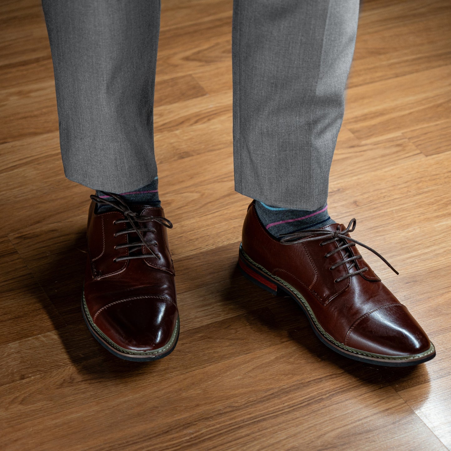 A grey men's dress sock with navy blue, white, pink and light blue stripes