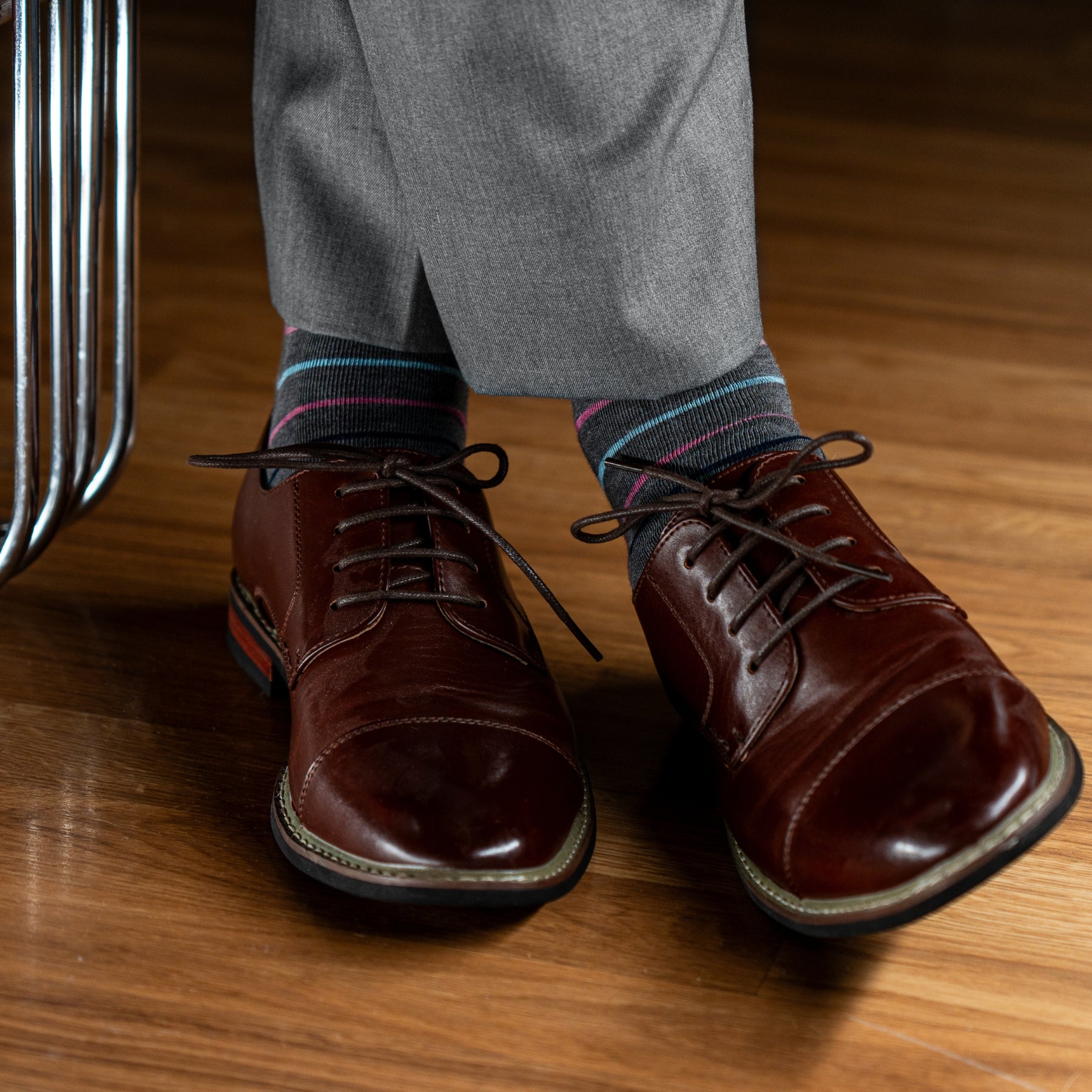 A grey men's dress sock with navy blue, white, pink and light blue stripes