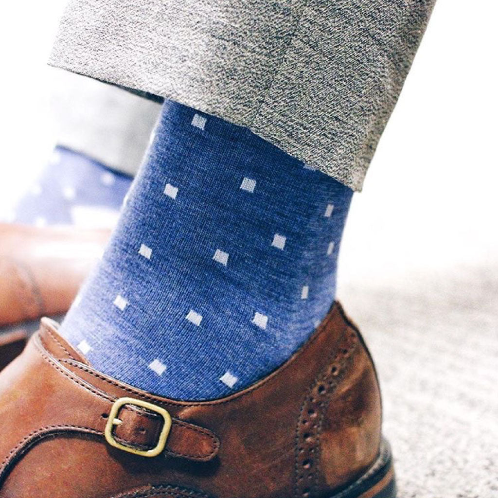 a guy wearing blue socks with light blue polka dots, grey trousers, and brown shoes