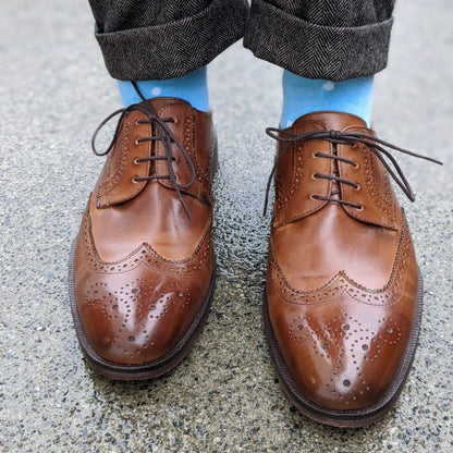 Man wearing baby blue and white polka dot socks, and dress shoes.