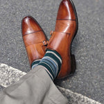 Man wearing green, taupe, and tan striped socks with dress shoes