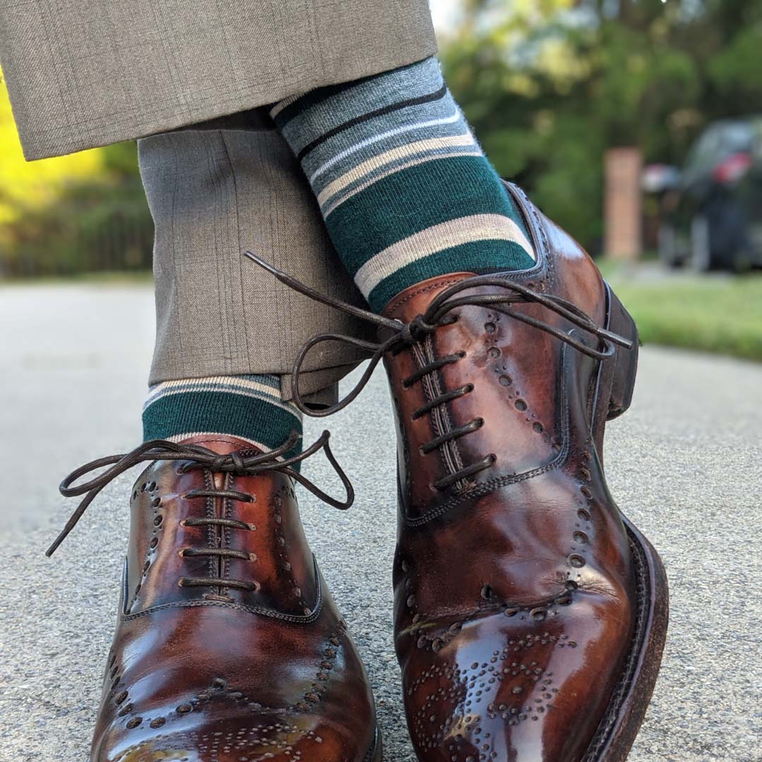 Man wearing green, taupe, and tan striped socks with dress shoes