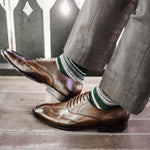Man wearing green, taupe, and tan striped socks with dress shoes