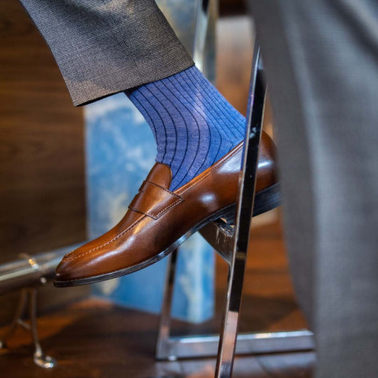 Man wearing solid, blue, and navy blue ribbed men's dress socks and brown shoes.