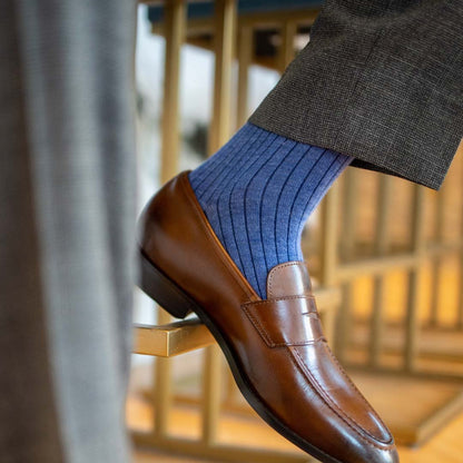 Man wearing solid, blue, and navy blue ribbed men's dress sock and brown shoe.