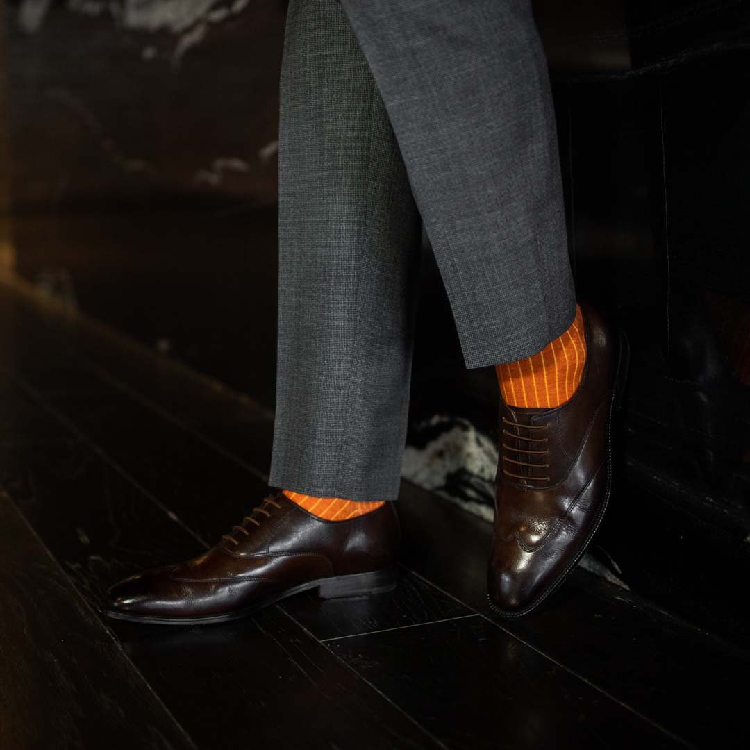 Man wearing orange, solid, tangerine ribbed men's dress socks.