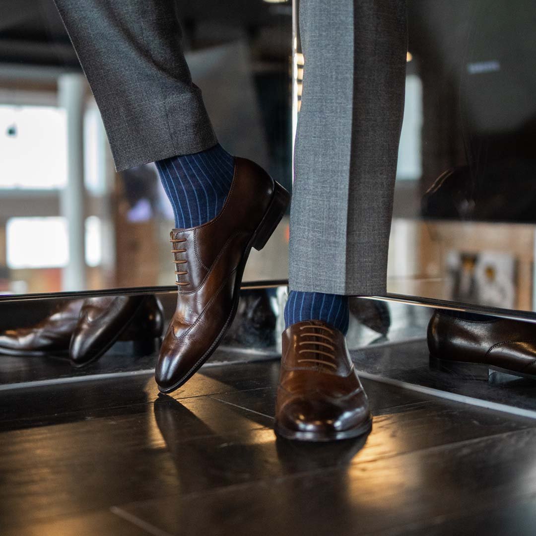 Man wearing midnight blue, solid, ribbed men's dress socks with brown shoes.