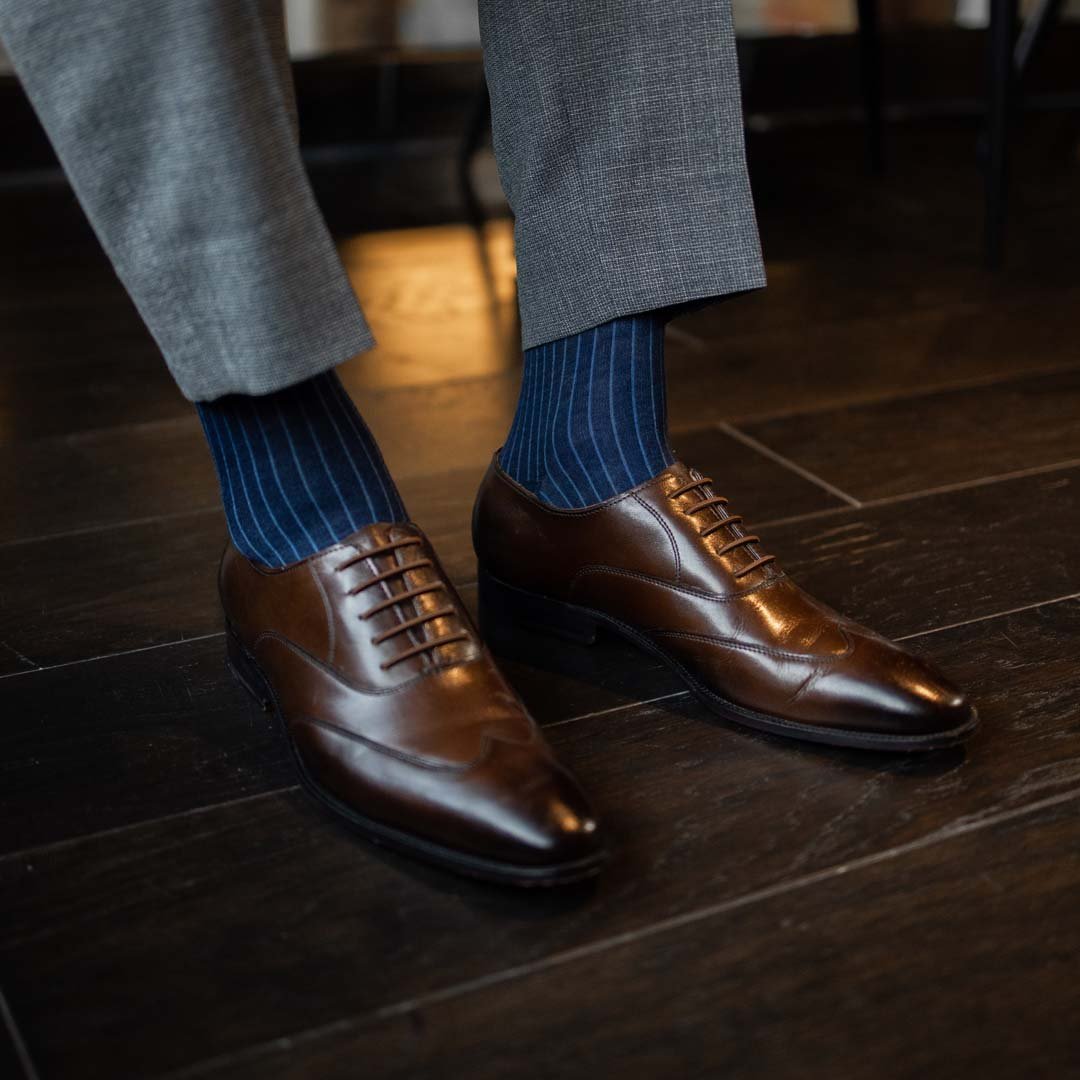 Man wearing midnight blue, solid, ribbed men's dress socks with brown shoes.