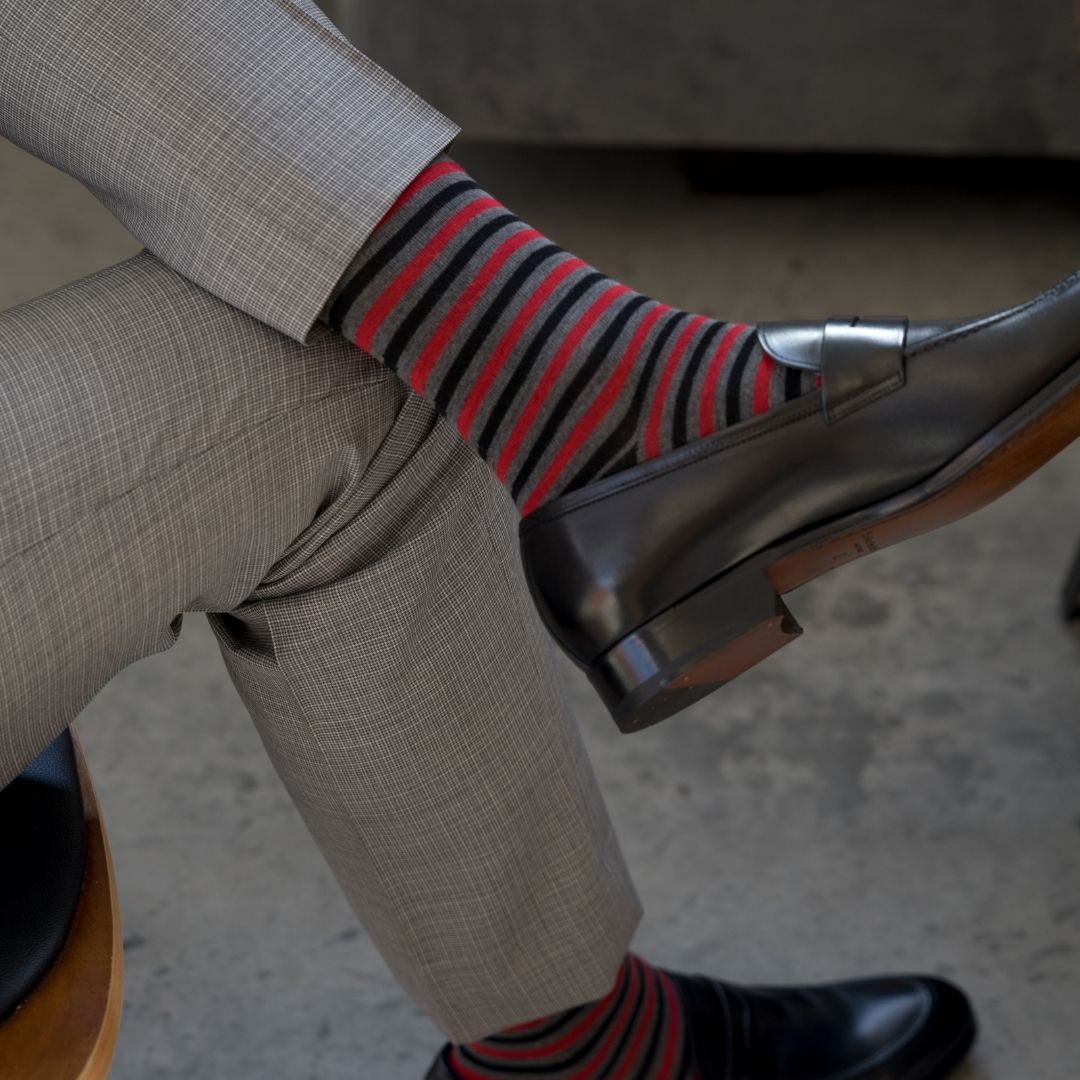 Man wearing charcoal grey, red, and black striped sock