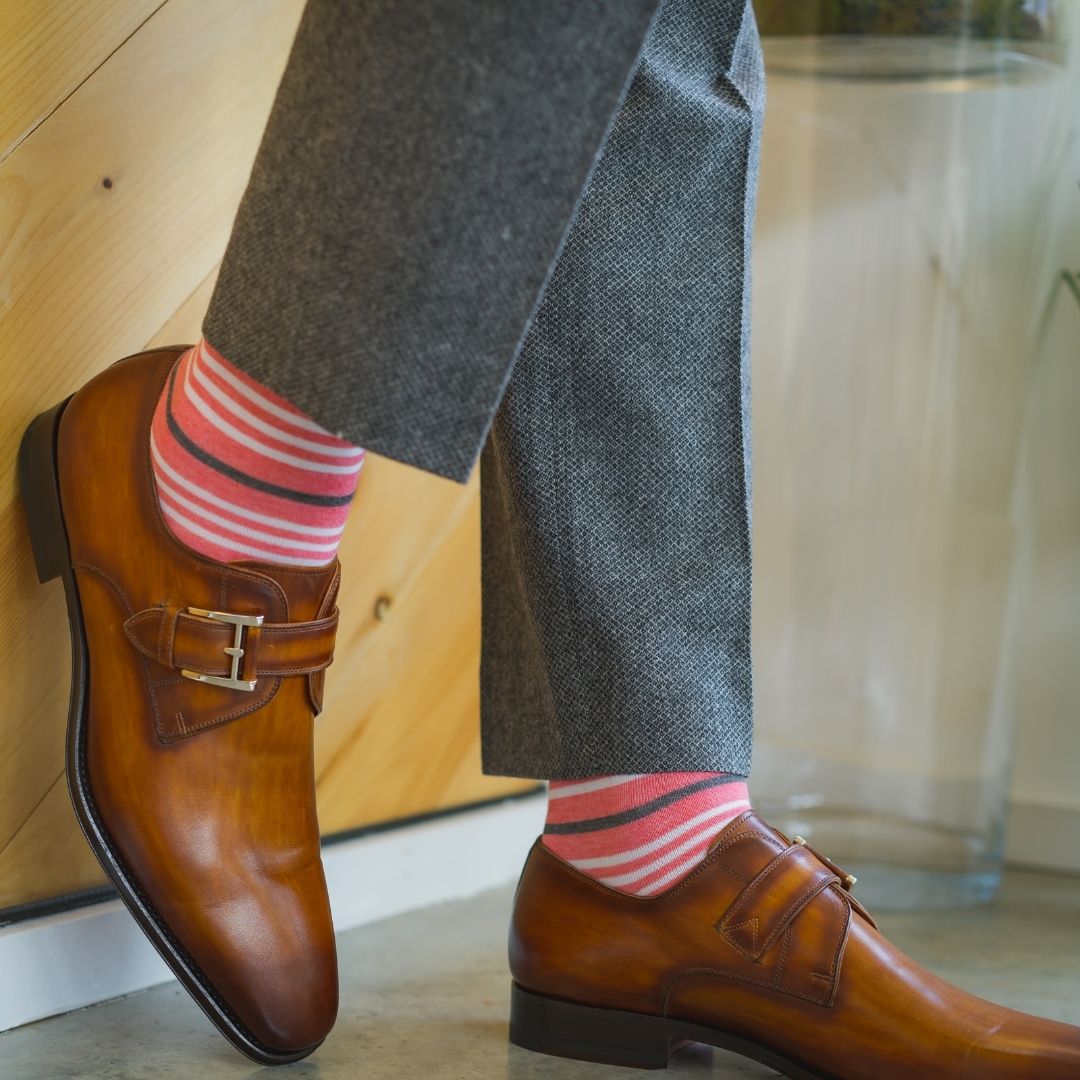 Man wearing coral, grey and white striped socks and dress shoes