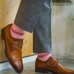 Man wearing coral, grey and white striped socks and dress shoes