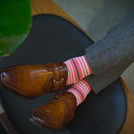 Man wearing coral, grey and white striped socks and dress shoes