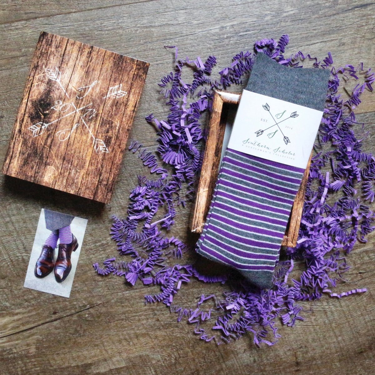 A pair of purple, grey, and white striped men's dress socks and gift box