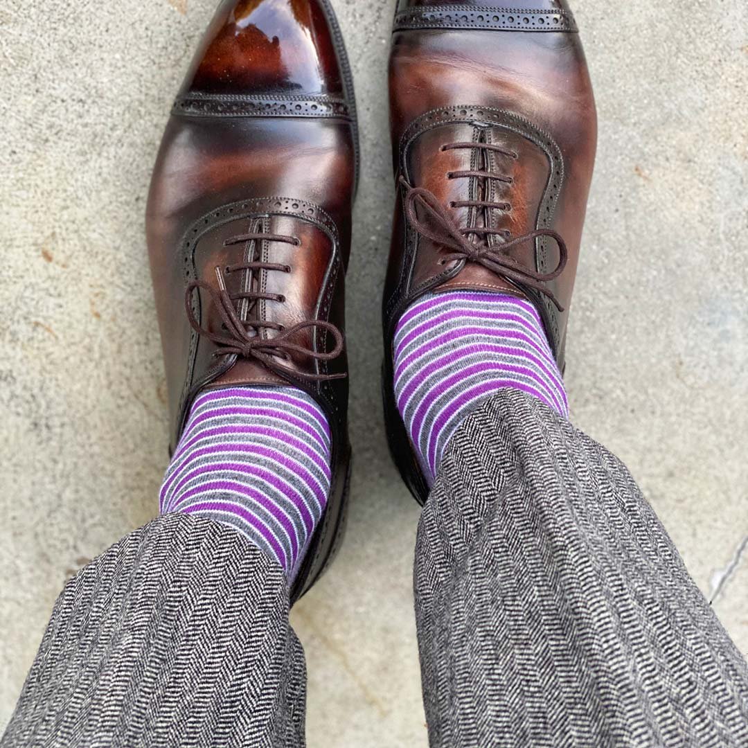 Man standing wearing purple, grey, and white striped dress socks and brown dress shoes